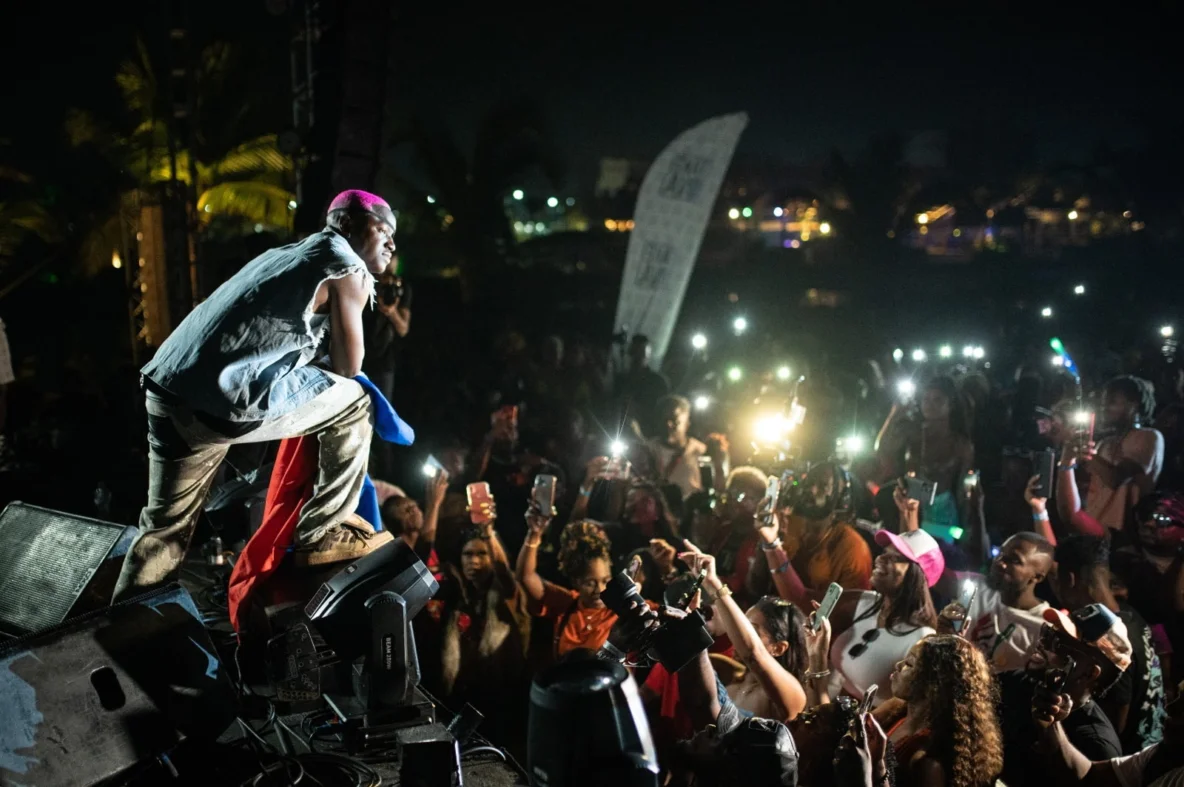 Artist Ruger performing on stage at a festival in Punta Cana in front of a crowd with glowing phones