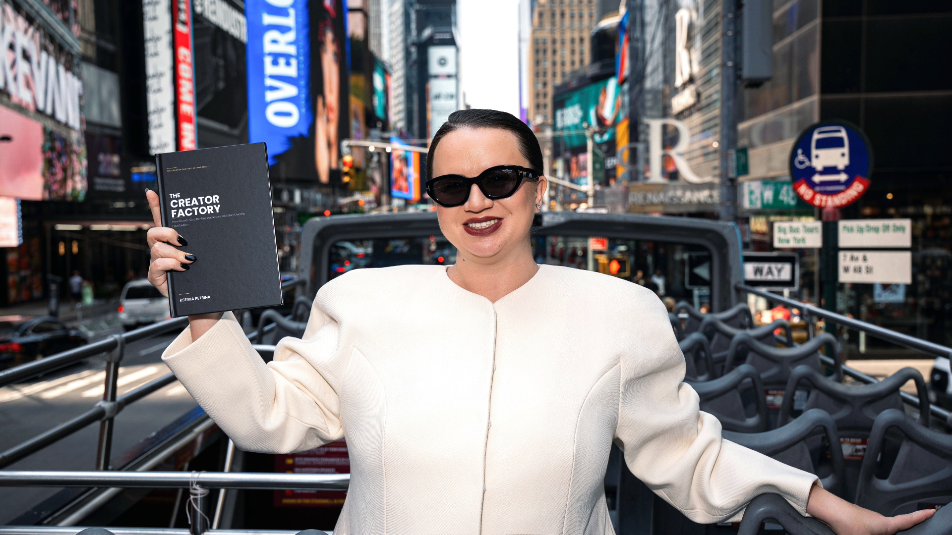 Kseniia Petrina holding The Creator Factory book in Times Square, New York