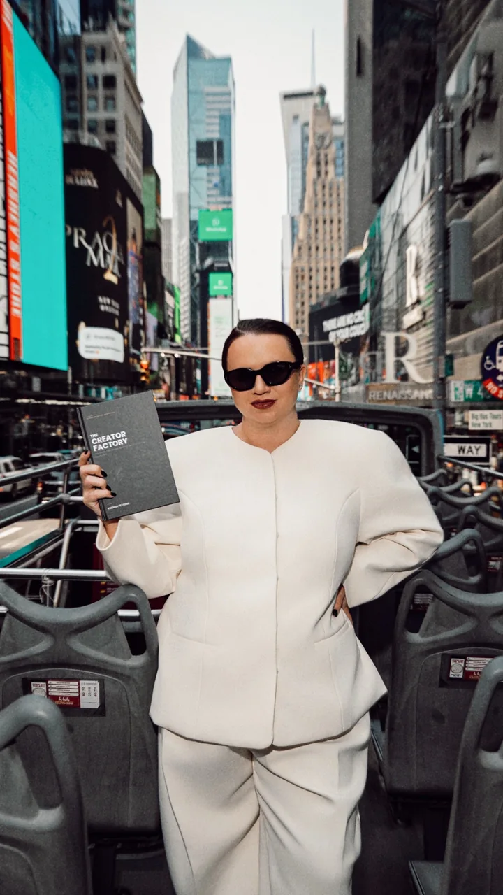 Kseniia Petrina in sunglasses holding The Creator Factory in Times Square, New York